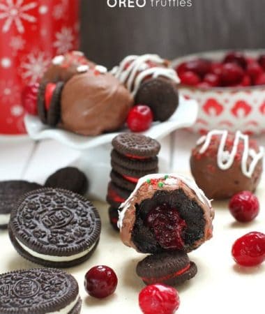 Half of a cranberry stuffed oreo truffle showing the inside with oreos and cranberries scattered nearby
