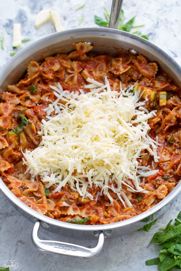 A pot of skillet lasagna with a handful of grated cheese on top