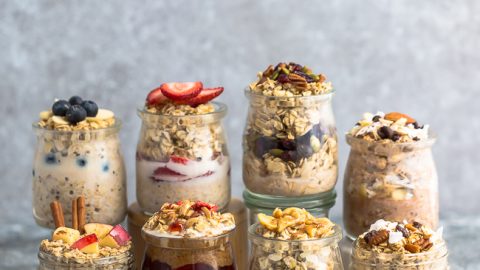 Eight Lined-Up Mason Jars Filled with Flavored Overnight Oats