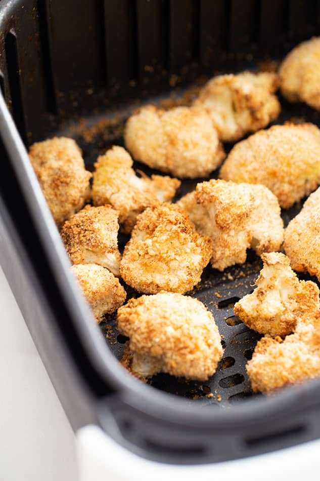 A close-up shot of cooked cauliflower wings inside of an Air Fryer basket