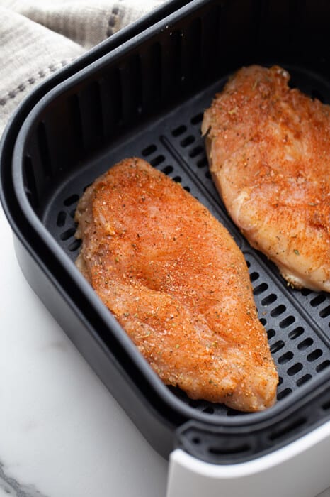 Top view of seasoned chicken breast in the air fryer
