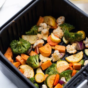 Fresh chopped zucchini, carrots, broccoli and cauliflower in an air fryer basket