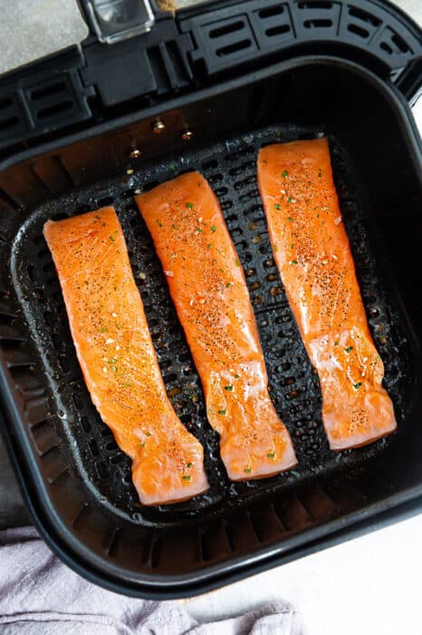 Three Salmon Fillets Placed Evenly Apart in an Air Fryer Basket