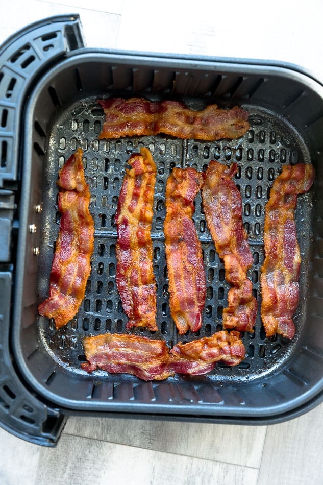 Seven Pieces of Cooked Bacon Inside of an Air Fryer Basket