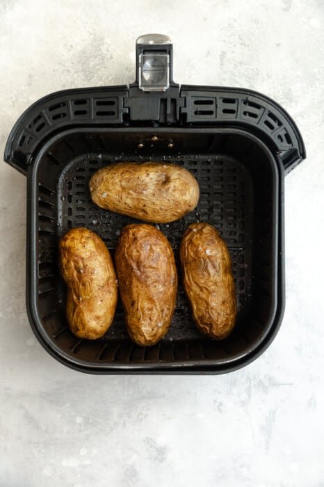 Overhead view of 4 baked potatoes in an air fryer
