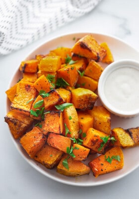 A plate of air-fried butternut squash with a striped kitchen towel behind it