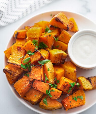 A plate of air-fried butternut squash with a striped kitchen towel behind it