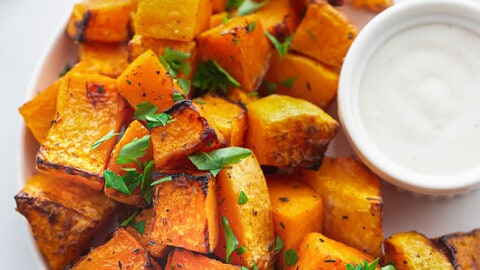 A plate of air-fried butternut squash with a striped kitchen towel behind it