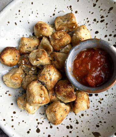 A Plate of Cauliflower Gnocchi with a Small Jar of Marinara Sauce on the Side