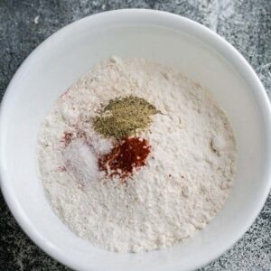 Seasonings to make air fryer chicken breading in a white bowl on a dark grey background