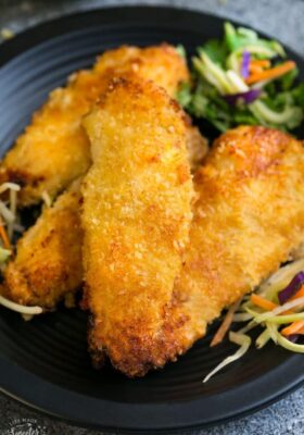 Close-up view of Air Fryer Chicken tenders on a black plate with coleslaw