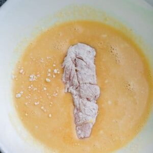 A Piece of Chicken Sitting in the Coconut Milk Marinade in a Bowl