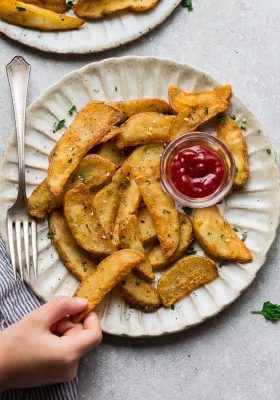 Plate of air fried potato wedges with a cup of ketchup