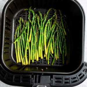 Top view of air fried asparagus in an air fryer basket