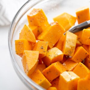 A close-up shot of the squash cubes being tossed with the seasoning blend