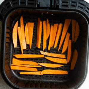Raw sweet potato fries in the air fryer basket
