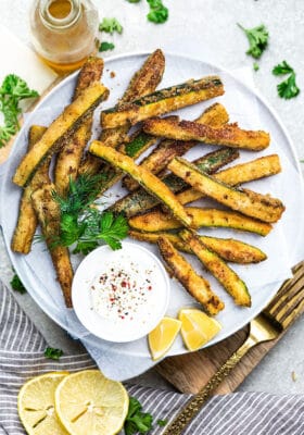 Crispy keto zucchini fries on a plate lined with parchment paper
