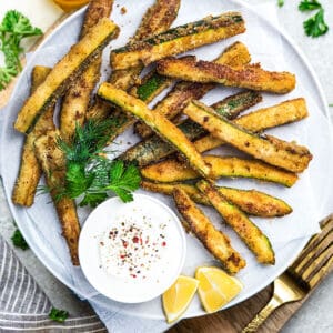 Crispy keto zucchini fries on a plate lined with parchment paper