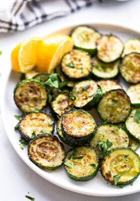 Side shot of air fryer zucchini rounds on a white plate