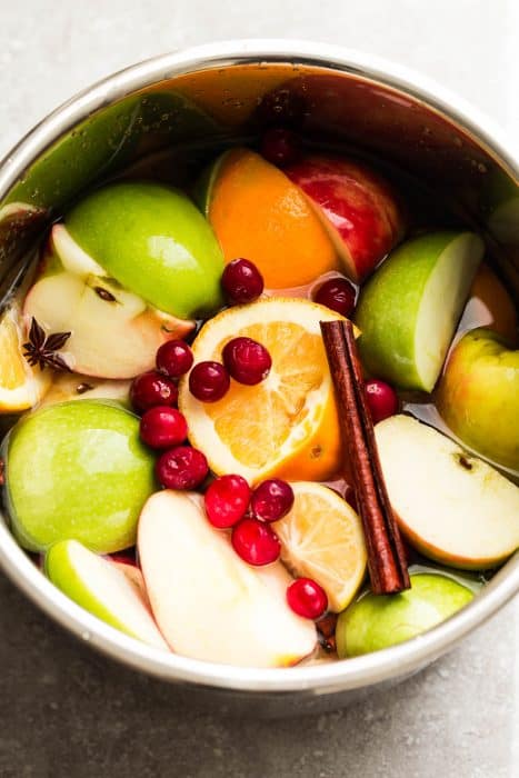 Top view of apples, oranges, cinnamon and cloves in an Instant Pot pressure cooker