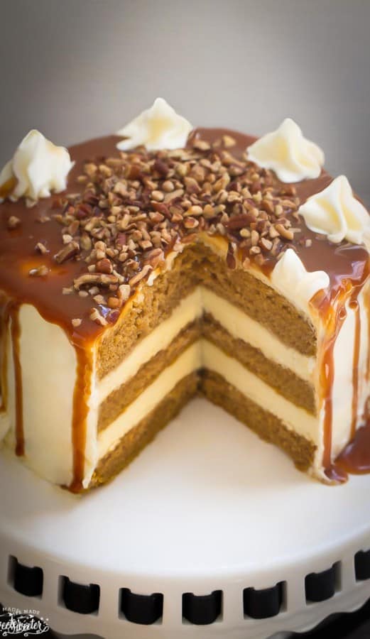 Apple Cider Spice Cake with Salted Caramel Drizzle on a white cake stand with a slice removed