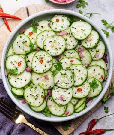 Asian Cucumber Salad with chili peppers, sesame seeds and fresh herbs in a white bowl