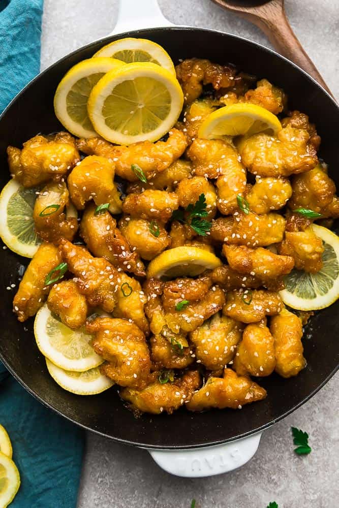 Overhead view of Asian lemon chicken in a skillet with lemon slices, garnished with sesame seeds