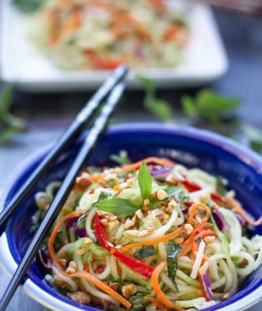 Top view of a serving of Zucchini noodle salad in a blue bowl with chopsticks on top
