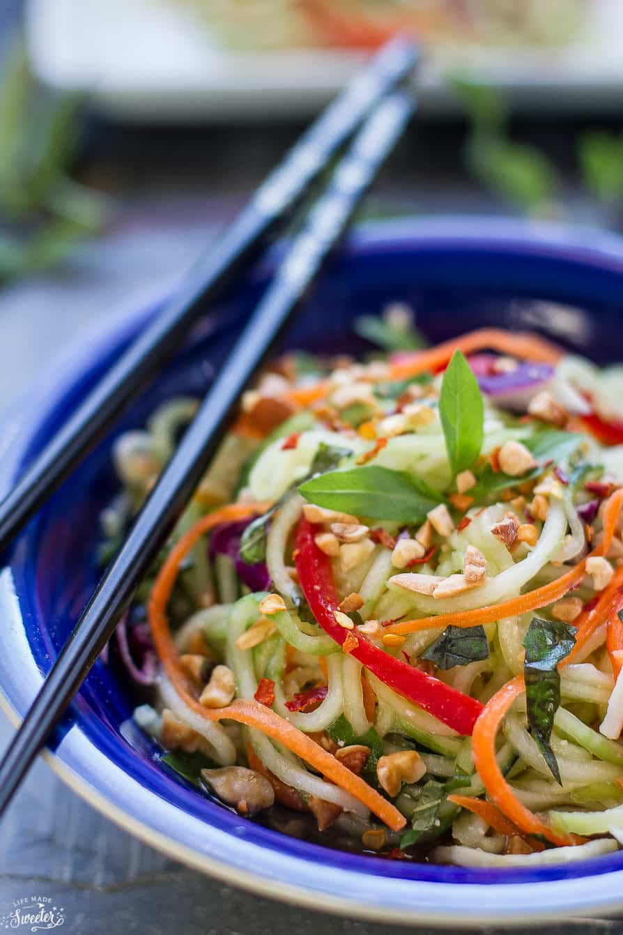 Close-up view of a serving of Zucchini noodle salad in a blue bowl with chopsticks on top