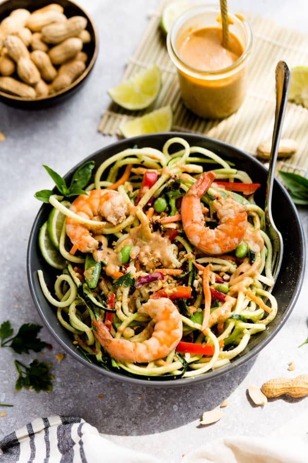 A serving of Asian Zucchini Noodle Salad with Thai Peanut Dressing topped with shrimp in a bowl