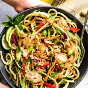 Top view of a large serving bowl of Asian zucchini noodle salad with chicken and vegetables