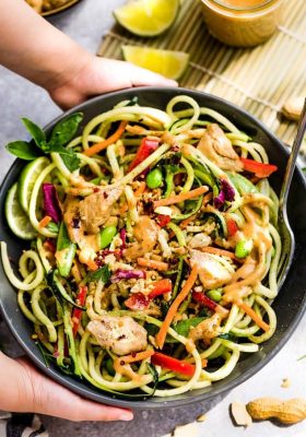 Top view of a large serving bowl of Asian zucchini noodle salad with chicken and vegetables