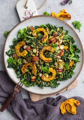 Top view of Fall Salad with Kale & roasted delicata squash in a bowl with a copper fork