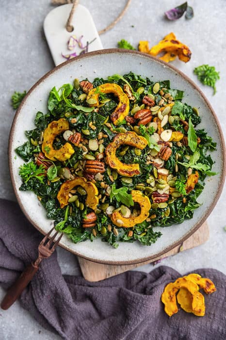 Top view of Fall Salad with Kale & roasted delicata squash in a bowl with a copper fork