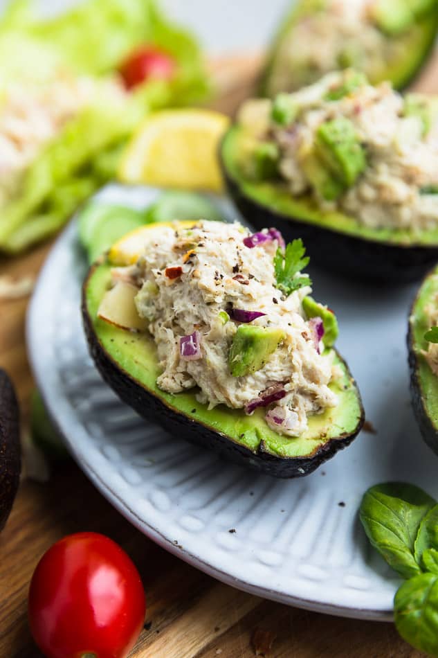 Close up side view of Whole30 avocado chicken salad in 3 avocado halves on a white plate