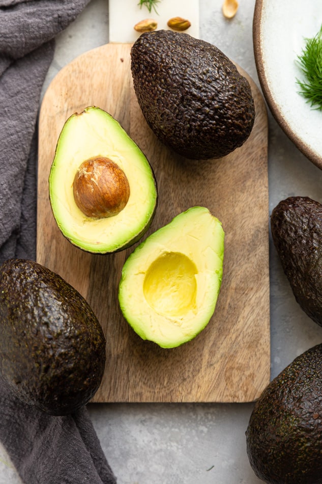 Top view of two halved avocados on a wooden cutting board