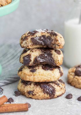 Side view of 4 partially eaten Keto Chocolate Chip Cookies stacked with a milk jug behind