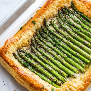 An entire baked asparagus tart on a baking sheet