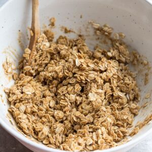 A Bowl Filled with Oat mixture being mixed with a Wooden Spoon