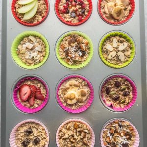 Twelve Unbaked Oatmeal Cups with Different Toppings in a Muffin Tin