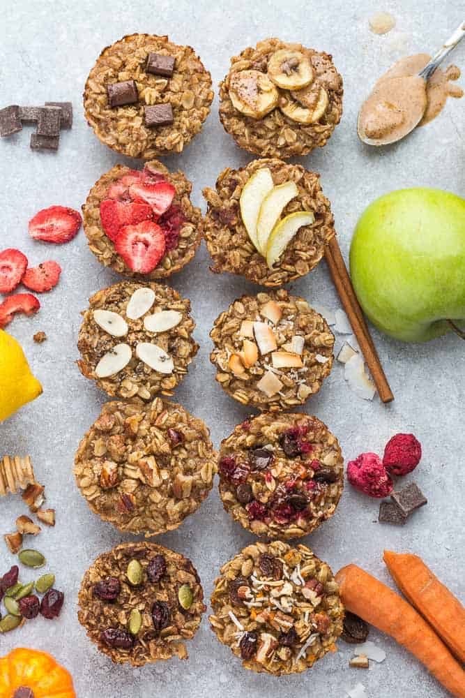 10 baked oatmeal cups surrounded by lemons, blueberries, strawberries and apples.