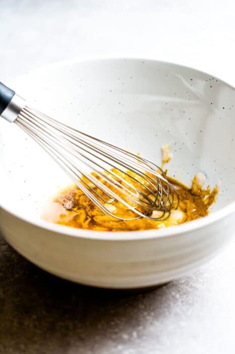 Egg and Maple Syrup Mixture Being Whisked In a White Bowl