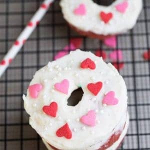 Baked Red Velvet Cake Donuts with Cream Cheese Glaze and heart shaped sprinkles on a cooling rack