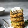 A stack of five salmon cakes topped with a dollop of homemade Greek yogurt sauce