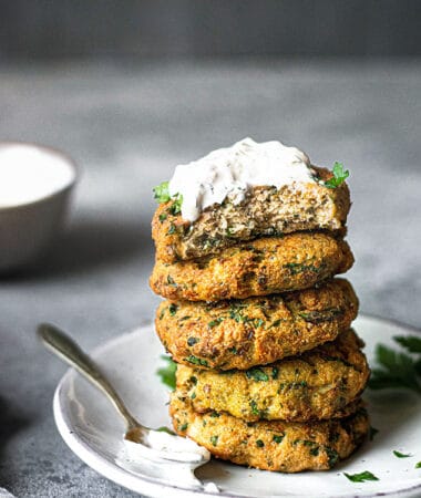 Side view of salmon cakes stacked on a white plate