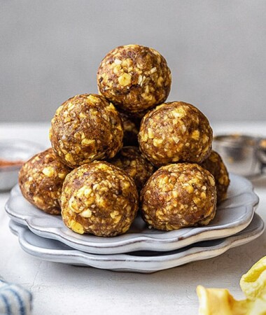 Side view of a stack of 6 banana protein balls on a white plate