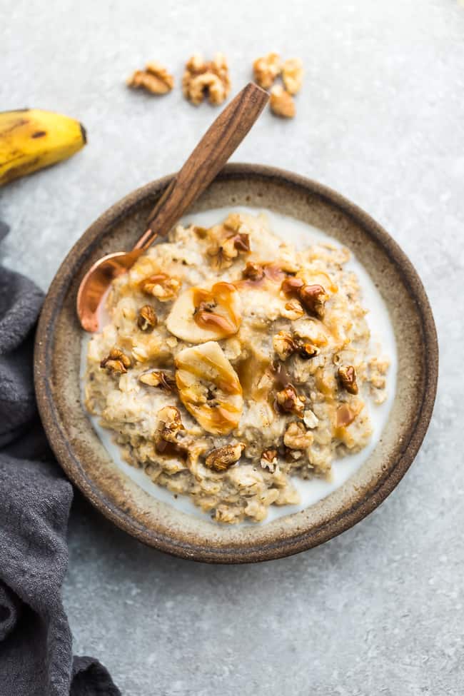 A bowl of banana oatmeal on a kitchen counter with a spoon inside