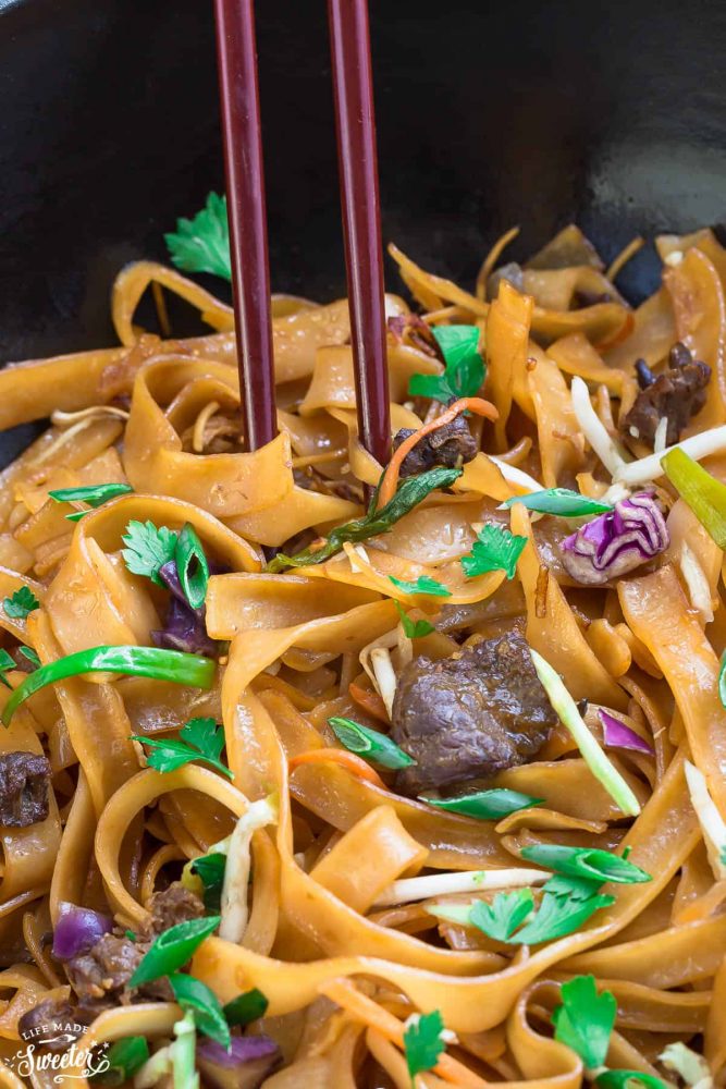 Authentic Fried Ho Fun Noodles with cabbage and green onions with red chopsticks.