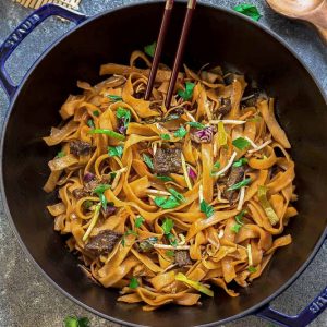 Simple Beef Chow Fun noodles in a blue dish with wooden chopsticks.