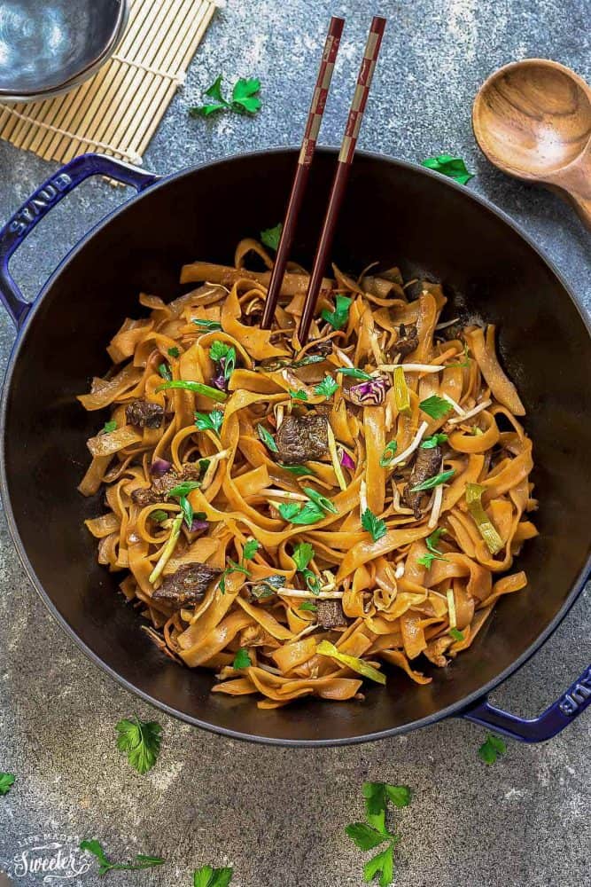 Beef Chow Fun noodles in a dark blue bowl with wooden chopsticks.